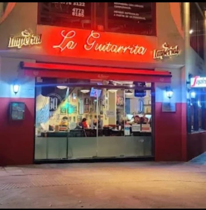 Fachada nocturna de La Guitarrita con cartel de neón rojo.