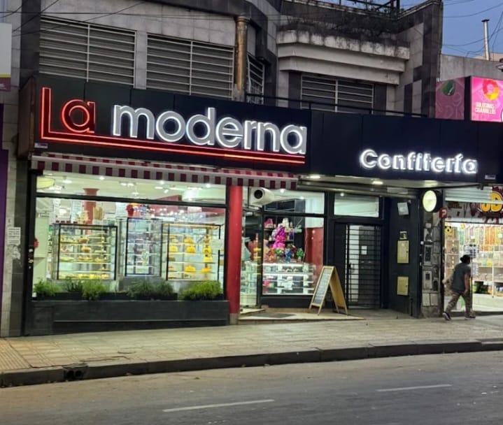 Fachada de La Moderna Confitería con cartelería iluminada.